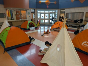 Tents in a school with students reading books in and around the tents