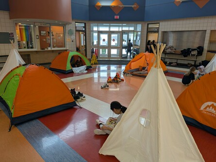 Tents in a school with students reading books in and around the tents